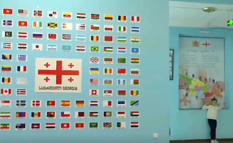 აფხაზეთის და რუსეთის დროშები სკოლის სტენდზე - ყოფილი დირექტორი "პირველების" კამერებს ემალება